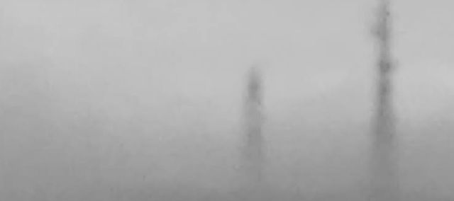 A blurred black and white image of two transmitter masts