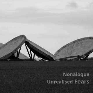 A black and white picture of dismantled parabolic radar dishes lying on the ground in a field.